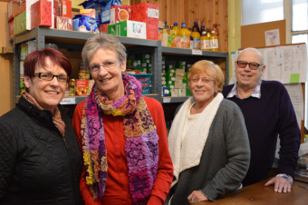 Photo of four people stood with shelves of food behind them