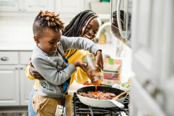 Photo of a woman and child cooking on a stove top